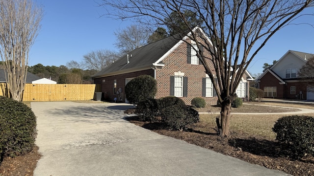 view of side of property with fence, concrete driveway, and brick siding