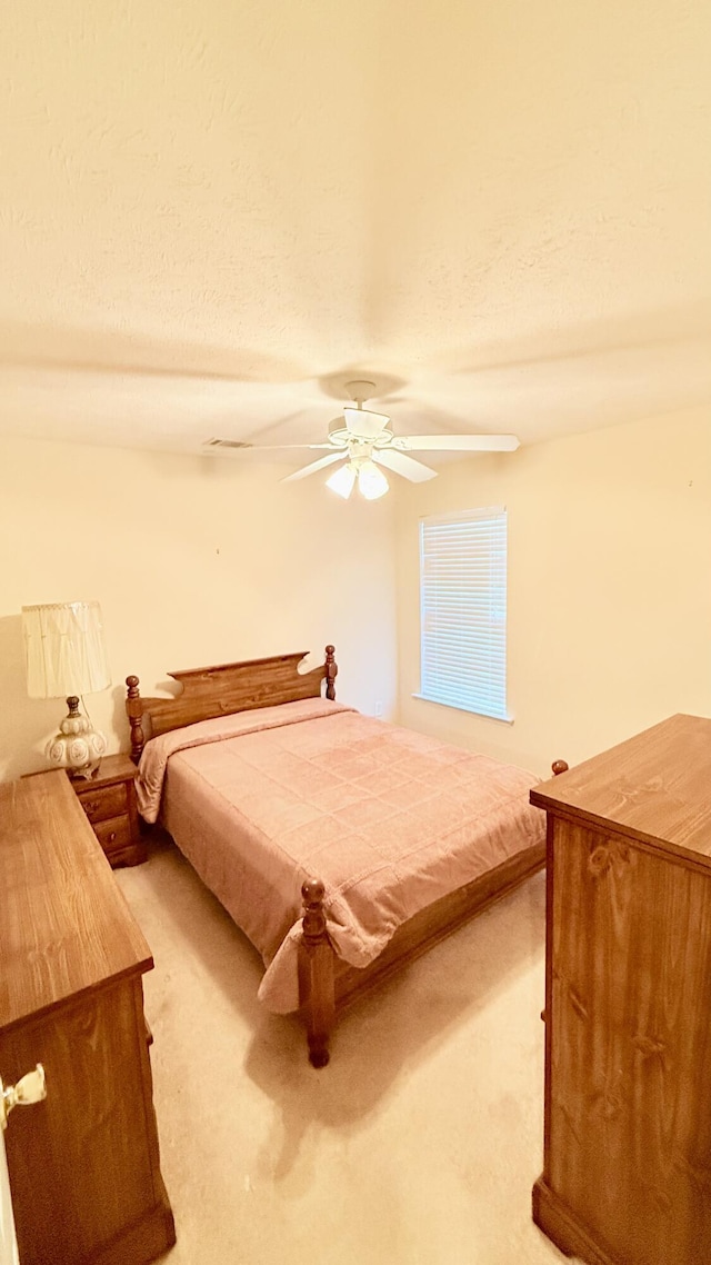 bedroom with light carpet, a textured ceiling, and a ceiling fan