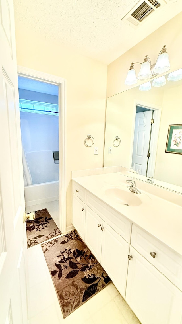 full bathroom with visible vents, vanity, and a textured ceiling