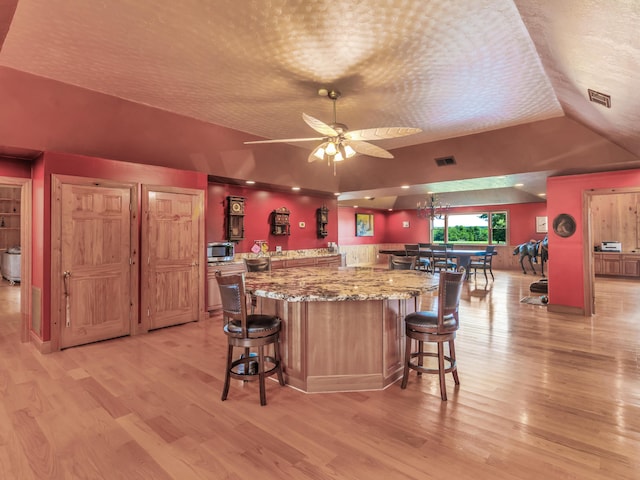 kitchen featuring a textured ceiling, light hardwood / wood-style floors, ceiling fan, and lofted ceiling