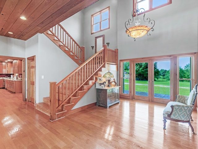 interior space with french doors, a towering ceiling, wooden ceiling, and light hardwood / wood-style floors