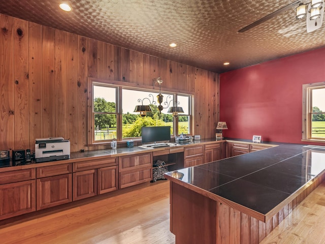 office area featuring ceiling fan, light hardwood / wood-style floors, and wooden walls