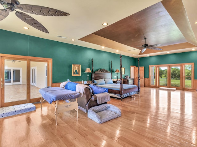 bedroom with french doors, a tray ceiling, light hardwood / wood-style flooring, and ceiling fan