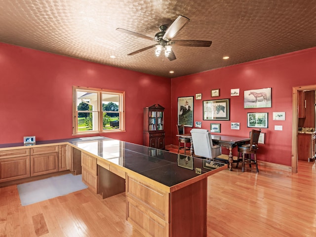 office area featuring ceiling fan, built in desk, and light hardwood / wood-style floors