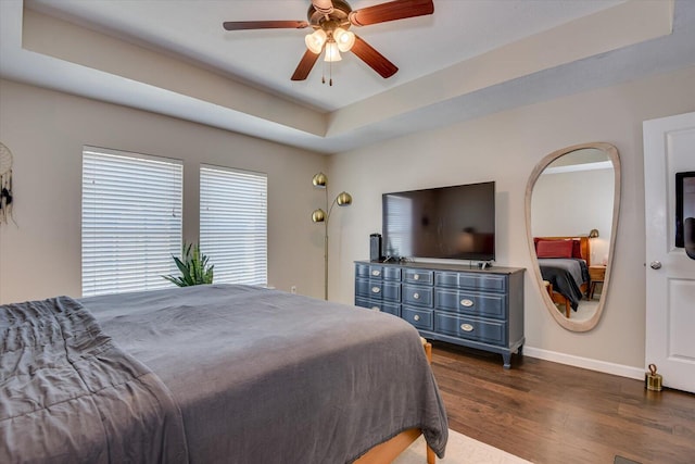 bedroom with ceiling fan, dark hardwood / wood-style floors, and a raised ceiling