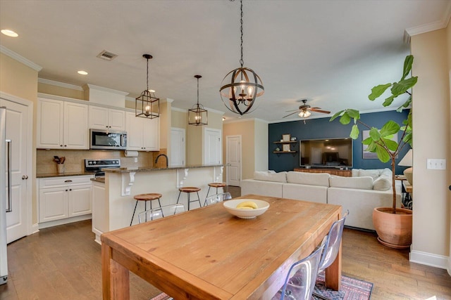 dining space with ceiling fan, ornamental molding, and light hardwood / wood-style flooring