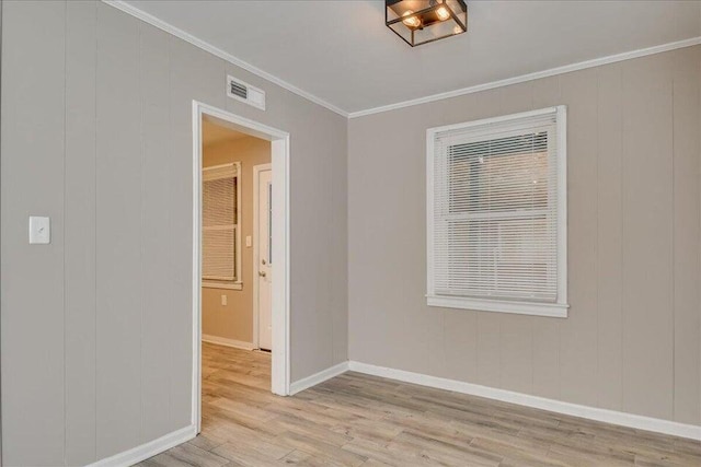 spare room featuring crown molding and light hardwood / wood-style floors