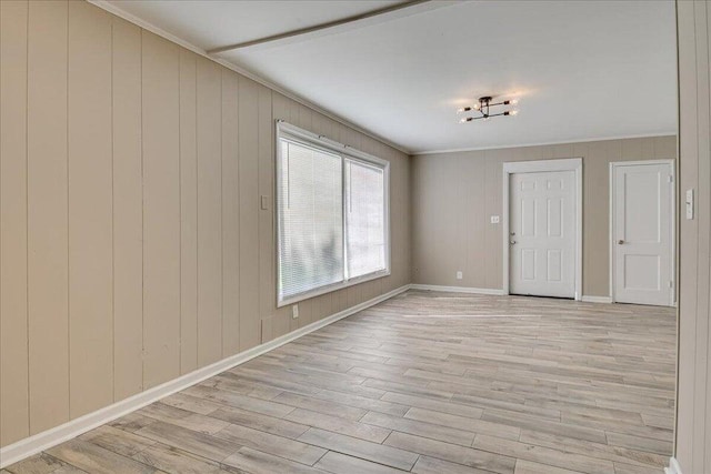 entrance foyer with ornamental molding, light wood-type flooring, and wood walls