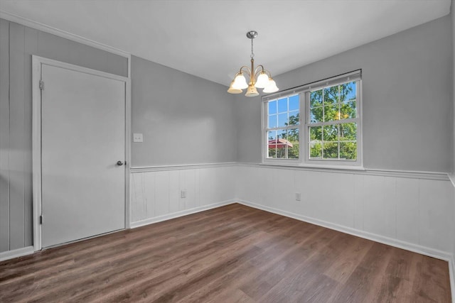 spare room featuring wood finished floors, a chandelier, and wainscoting