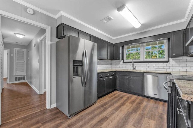 kitchen with stainless steel appliances, dark wood-style flooring, a sink, tasteful backsplash, and ornamental molding
