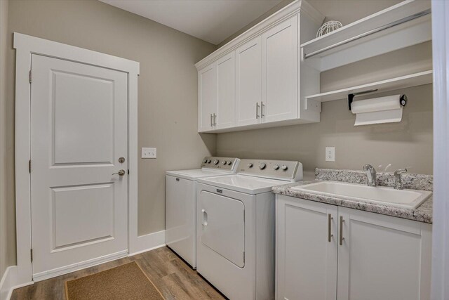 laundry area with cabinets, separate washer and dryer, light hardwood / wood-style floors, and sink