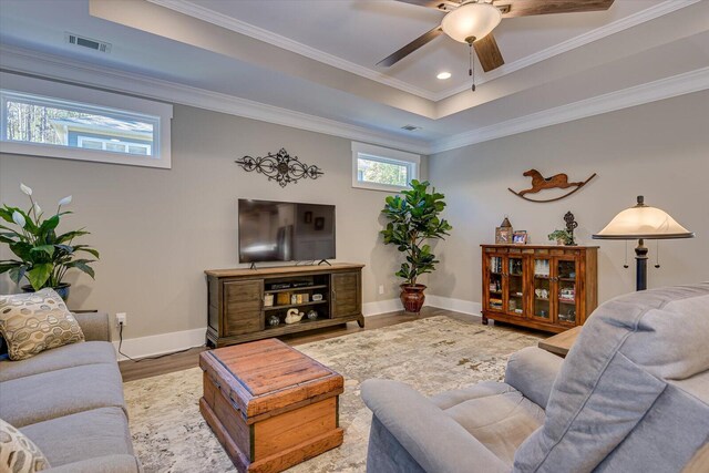 living room featuring a raised ceiling, crown molding, ceiling fan, and hardwood / wood-style flooring