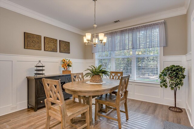 dining area featuring hardwood / wood-style floors, an inviting chandelier, and ornamental molding