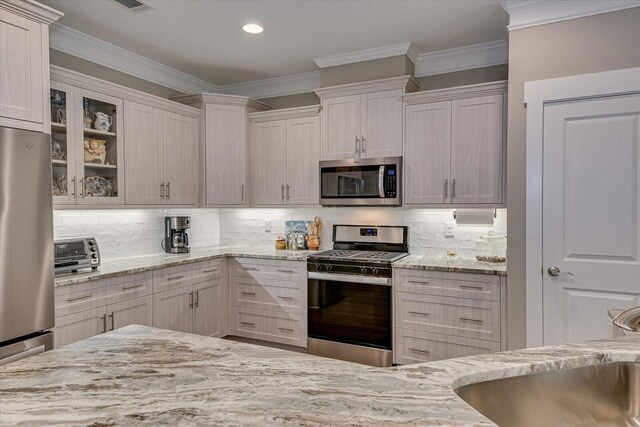 kitchen with backsplash, light stone counters, white cabinets, and stainless steel appliances