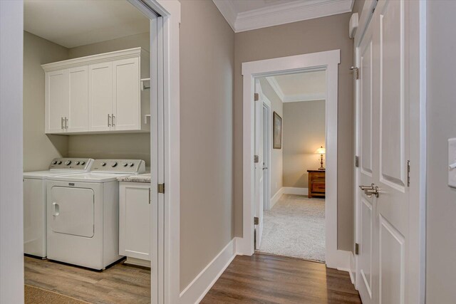 clothes washing area featuring separate washer and dryer, hardwood / wood-style flooring, cabinets, and ornamental molding