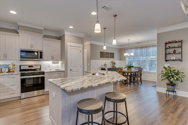 kitchen with pendant lighting, white cabinetry, a kitchen island with sink, and appliances with stainless steel finishes