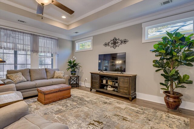 living room featuring hardwood / wood-style floors, ceiling fan, crown molding, and a tray ceiling