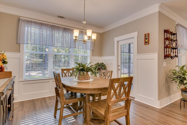 dining room with wood-type flooring, an inviting chandelier, and crown molding