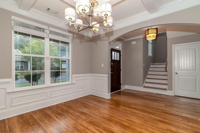 entryway featuring hardwood / wood-style flooring, ornamental molding, and an inviting chandelier