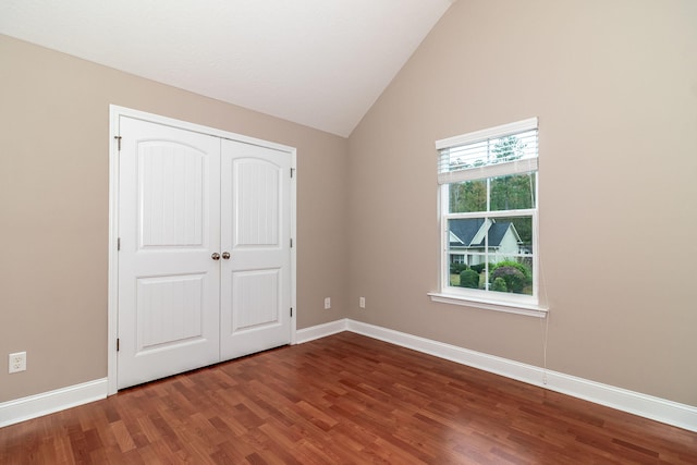 unfurnished bedroom with dark hardwood / wood-style floors, a closet, and vaulted ceiling