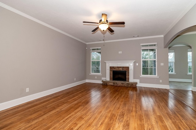 unfurnished living room featuring a stone fireplace, ceiling fan, light hardwood / wood-style floors, and ornamental molding