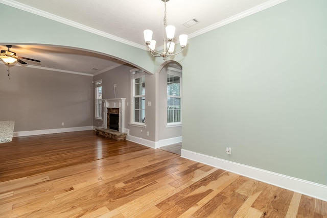 unfurnished living room featuring a healthy amount of sunlight, ceiling fan with notable chandelier, and ornamental molding