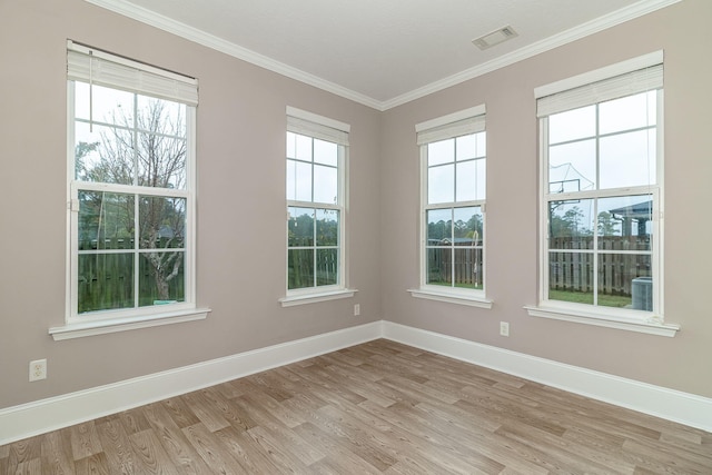 spare room featuring light wood-type flooring and crown molding