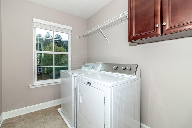 clothes washing area with cabinets, independent washer and dryer, and light tile patterned flooring