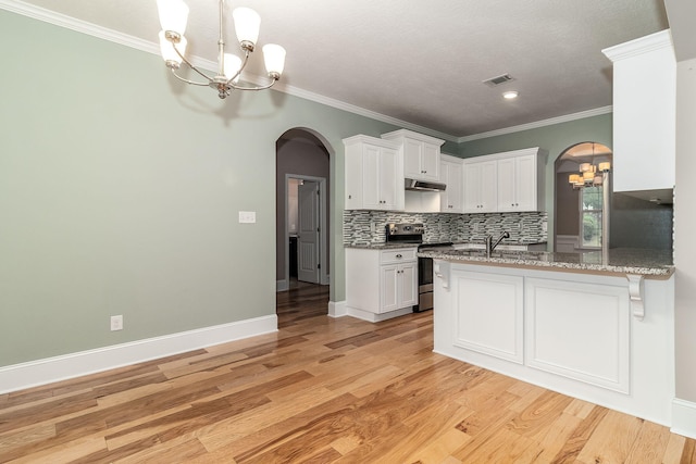 kitchen featuring tasteful backsplash, stainless steel range, white cabinets, and a notable chandelier