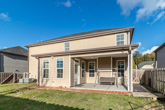 rear view of house featuring a lawn, cooling unit, and a patio