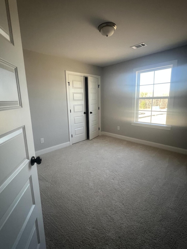 empty room featuring visible vents, baseboards, and carpet flooring