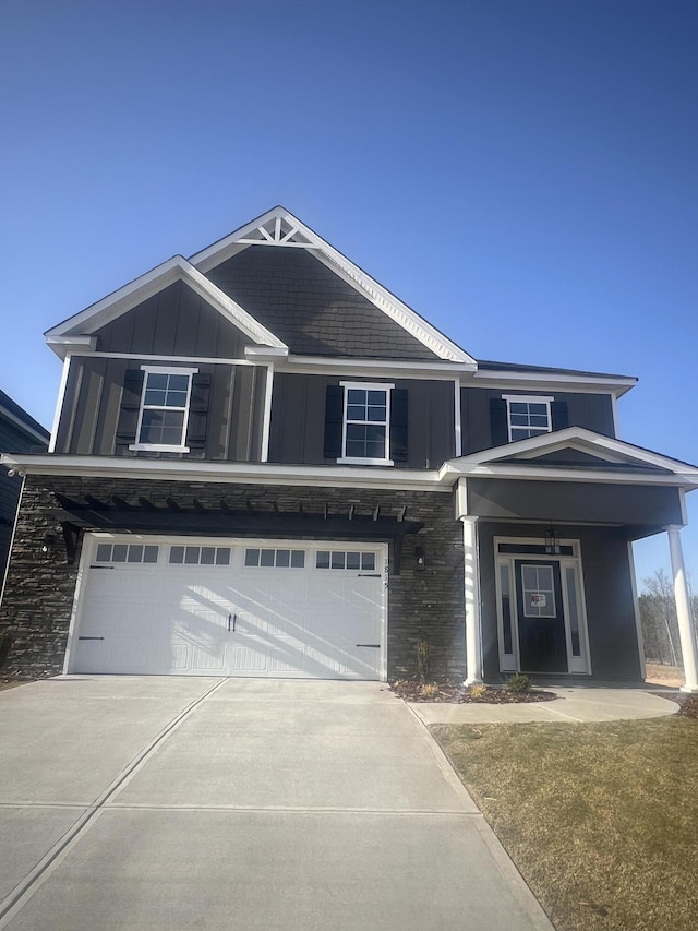 view of front of property featuring a garage, driveway, board and batten siding, and stone siding