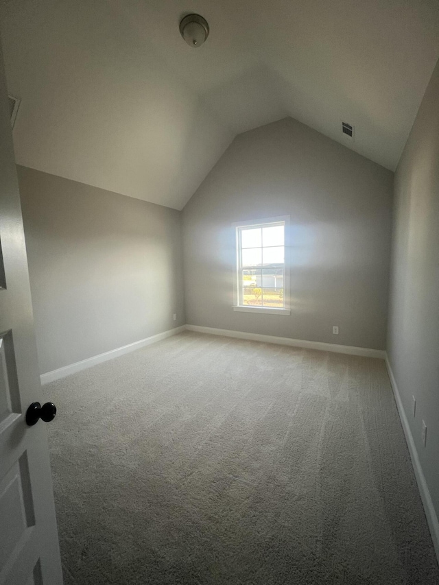 additional living space featuring carpet floors, lofted ceiling, visible vents, and baseboards