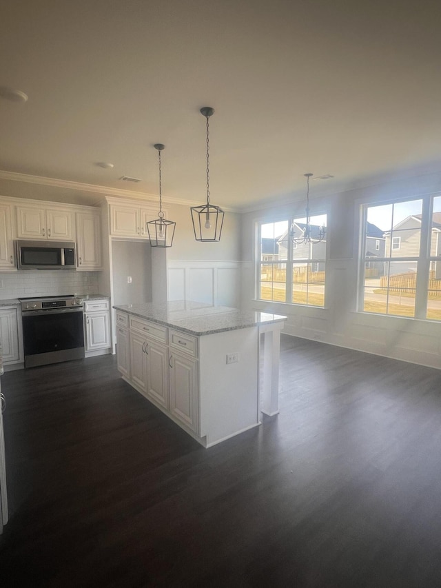 kitchen with appliances with stainless steel finishes, white cabinetry, ornamental molding, and dark wood-style floors