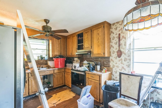 kitchen featuring electric stove, wood finished floors, wallpapered walls, under cabinet range hood, and freestanding refrigerator