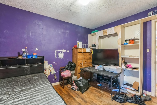 bedroom with baseboards, wood finished floors, and a textured ceiling