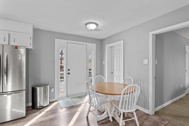 dining space with light hardwood / wood-style floors and a textured ceiling