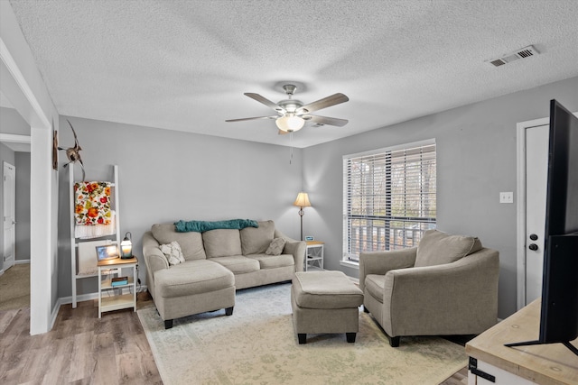 living room featuring ceiling fan, hardwood / wood-style floors, and a textured ceiling