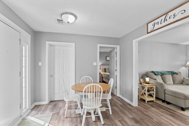 dining room with hardwood / wood-style flooring and a textured ceiling