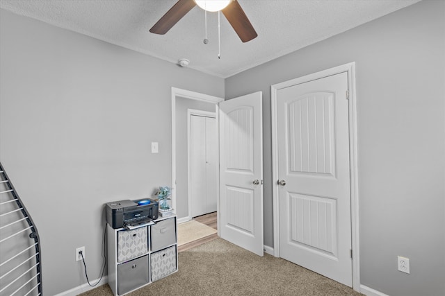 carpeted bedroom with ceiling fan, a closet, and a textured ceiling