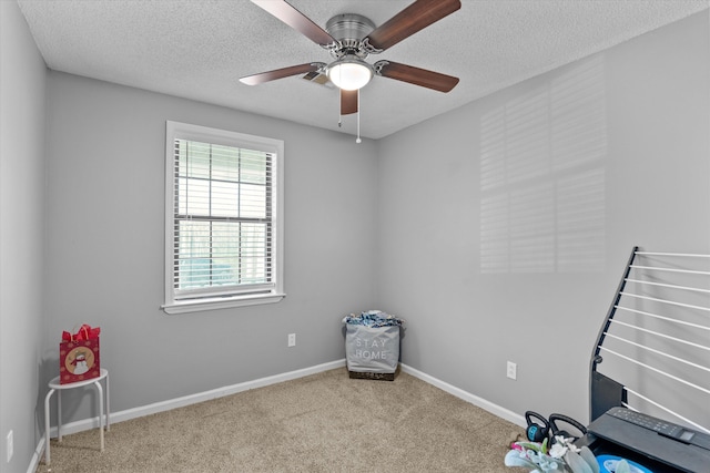 misc room featuring light carpet, ceiling fan, and a textured ceiling