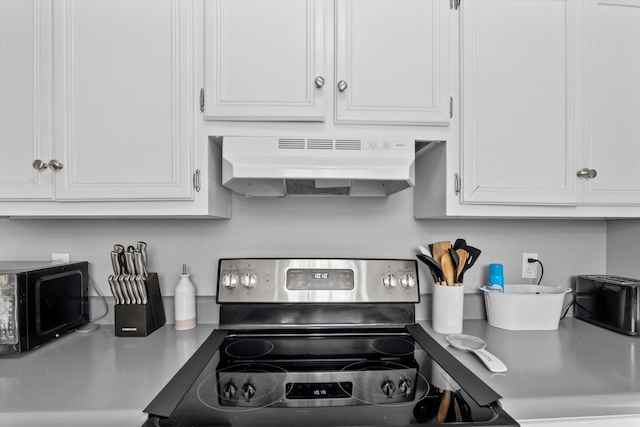 kitchen featuring stainless steel electric stove, white cabinets, and extractor fan