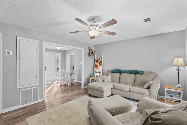 living room featuring a textured ceiling, ceiling fan, and dark hardwood / wood-style floors