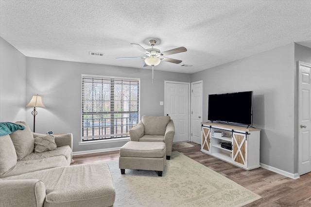 living room with ceiling fan, wood-type flooring, and a textured ceiling