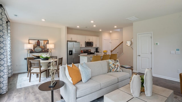 living area with light wood-type flooring, stairs, and recessed lighting