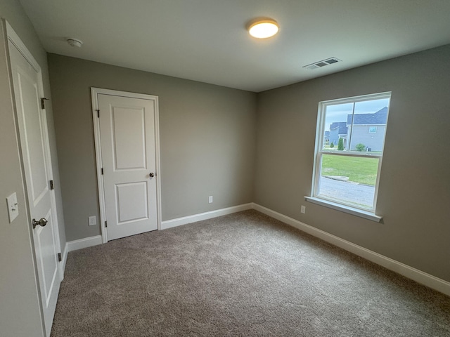 empty room featuring carpet floors, visible vents, and baseboards