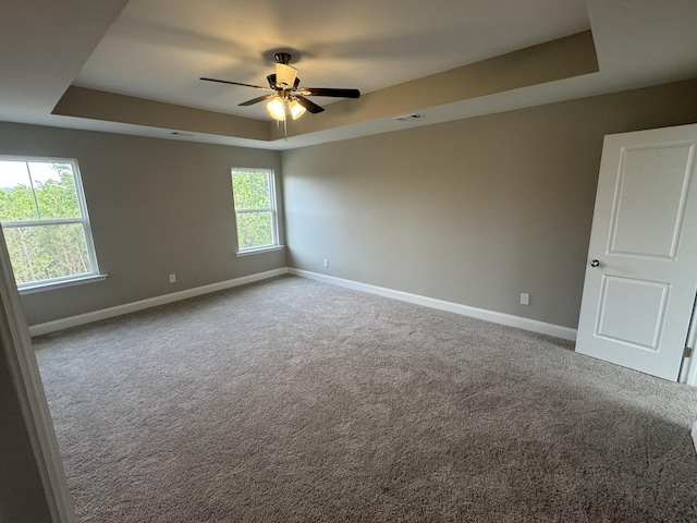 carpeted spare room with ceiling fan, baseboards, visible vents, and a raised ceiling