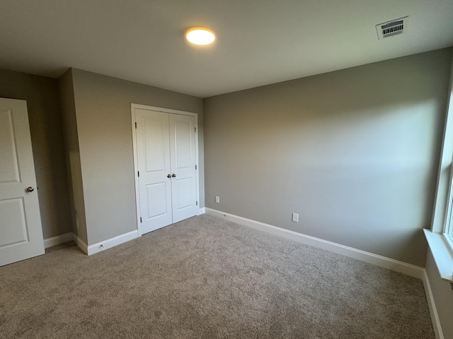 unfurnished bedroom with a closet, carpet floors, visible vents, and baseboards