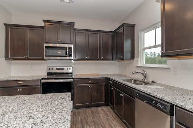 kitchen featuring dark wood-type flooring, sink, light stone countertops, dark brown cabinets, and stainless steel appliances