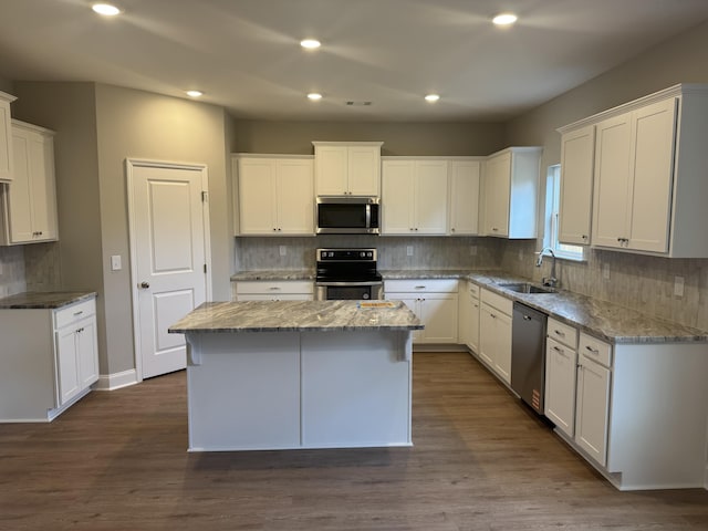 kitchen featuring tasteful backsplash, a sink, appliances with stainless steel finishes, light stone countertops, and a kitchen island